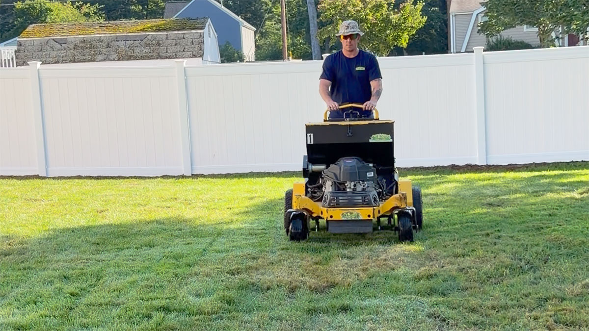Aeration machine pulling soil plugs from a New England lawn in early fall